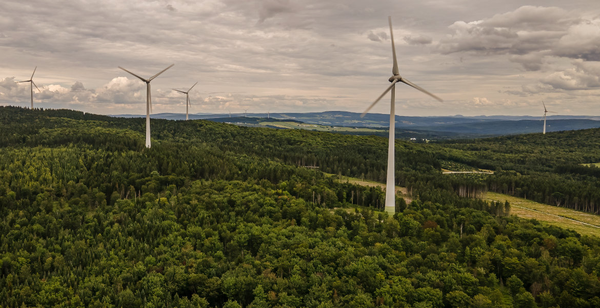 Tuulivoimaloita metsäisessä maisemassa