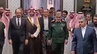 Osallistujia kokoontuneena sisätiloissa Teheranin tapaamisen yhteydessä, useita puvuissa, toisia saudiarabialaisessa asussa ja yksi vihreässä sotilaspuvussa